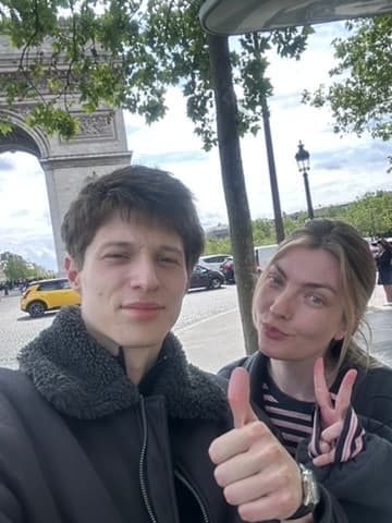 Mara and Samuel, thumbs up in front of the Arc de Triomphe in Paris
