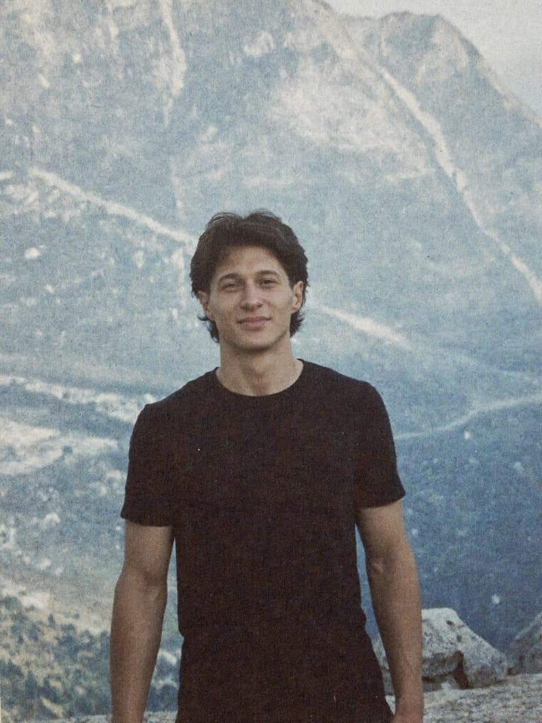 Samuel, standing in front of a snowy mountain face